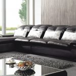 Черный диван со светлыми подушками в комнате
