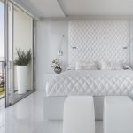 Белая кровать в спальне с большим окном